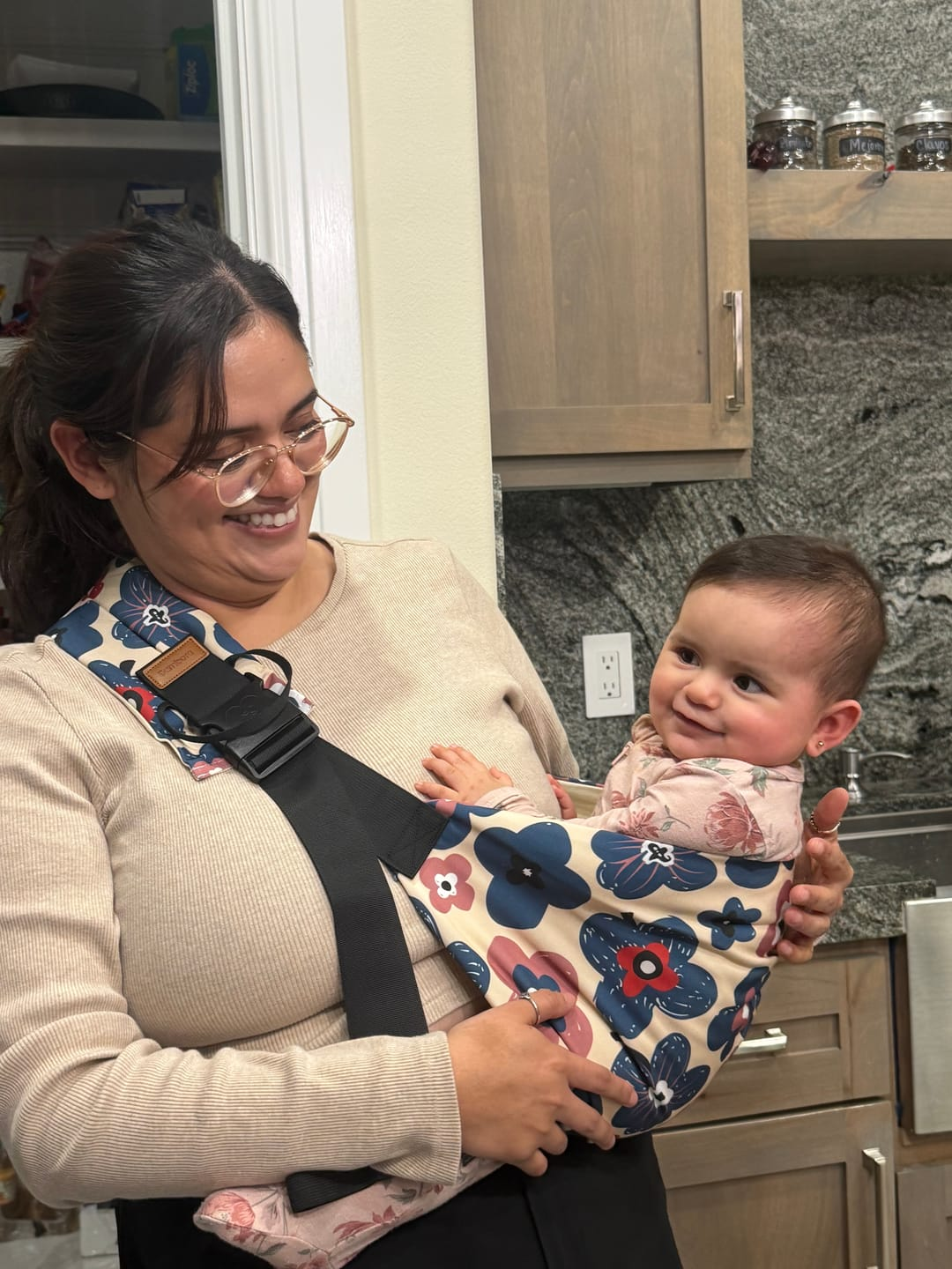 Smiling mom carrying her baby in a floral BrasDoux sling